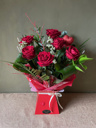 Poppy's Flower Design Florist in Leyland - Kissing Booth - Half dozen premium red roses arrange in luscious mixed foliage, completed with a beautiful heart shaped pick.